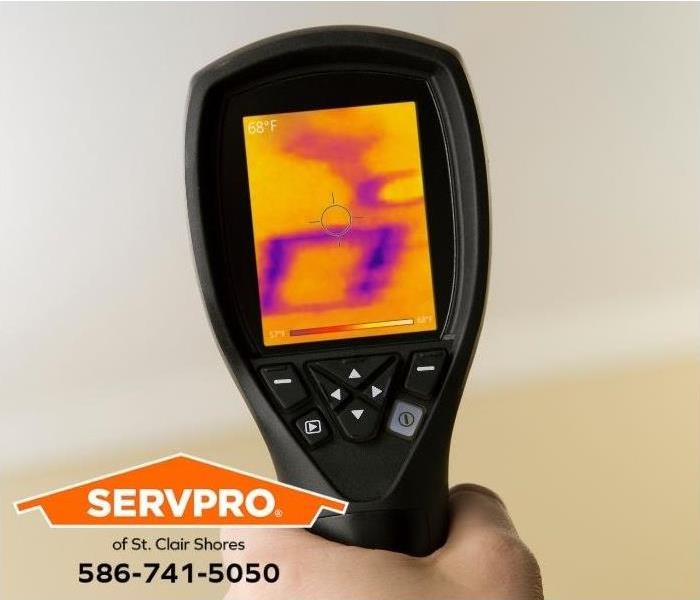 A technician uses an infrared camera to detect water damage on a wall. 