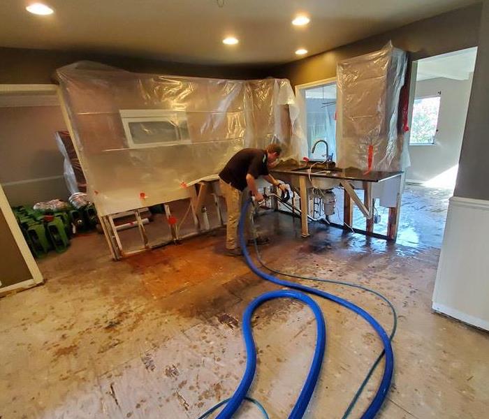 man steam cleaning sewage leak in kitchen that is gutted