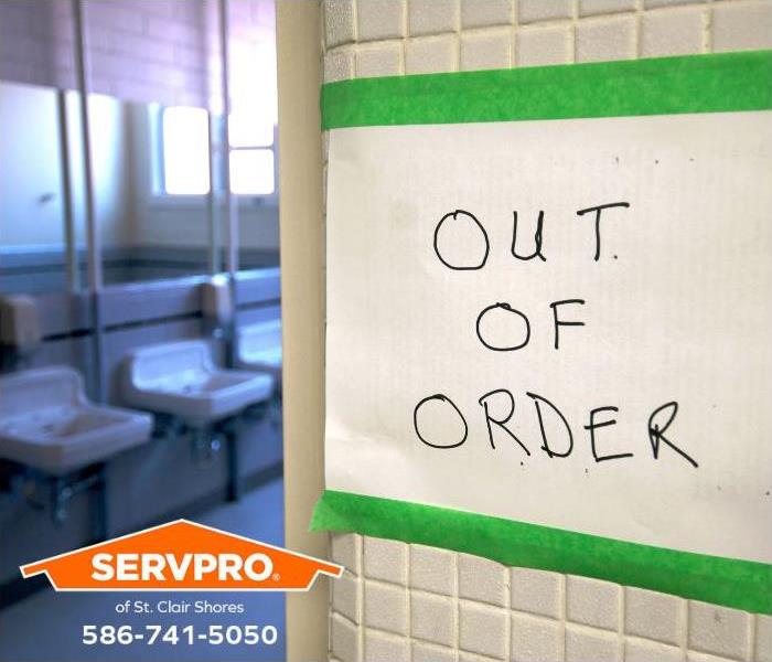 An out-of-order sign is taped to the entrance of a public restroom.