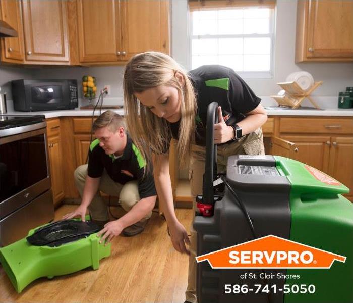 Technicians set up air blowers to remove excess moisture from a kitchen.