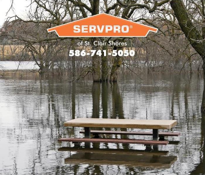 A picnic table is shown standing in water from a rising lake.