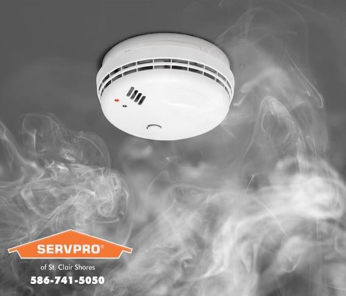 Smoke rises to meet a smoke detector mounted on the ceiling of a room. 